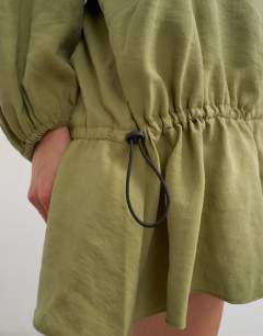 Model wearing Cupro funnel neck dropped waist long sleeve mini dress in khaki