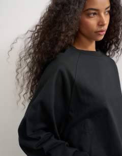 Model wearing Curve hem raglan sleeve skater t-shirt in black