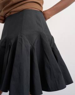 Model wearing Curved godet hem mini skirt in black