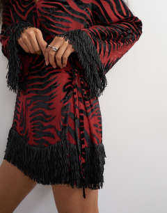 Model wearing Deep v mini wrap mini dress in red devore zebra with embellished fringed hem