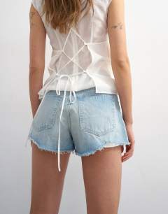 Model wearing Denim A-line short with rip in bleach