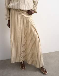Model wearing Denim asymmetric dropped waist maxi skirt in ecru stripe