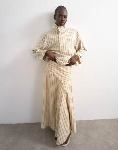 Model wearing Denim asymmetric dropped waist maxi skirt in ecru stripe