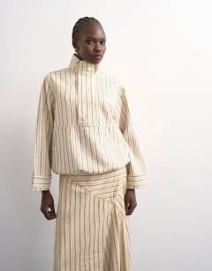 Model wearing Denim bubble hem top with funnel neck in ecru stripe