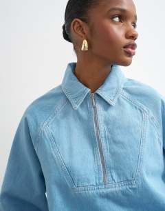 Model wearing Denim collared quarter zip blouson jacket in mid blue