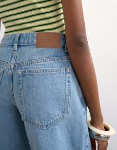 Model wearing Denim Editor short with rips in bleach