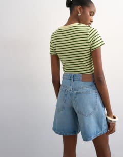 Model wearing Denim Editor short with rips in bleach