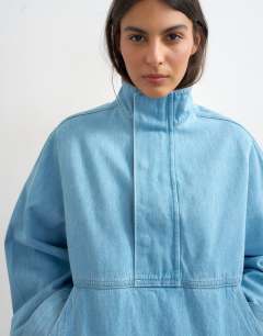 Model wearing Denim funnel neck bubble hem top in bleach