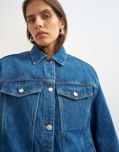 Model wearing Denim jacket with strong shoulder in mid blue