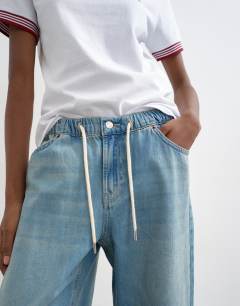 Model wearing Denim lightweight jogger jean in mid blue