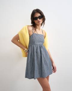 Model wearing Denim open back strappy dress in blue stripe