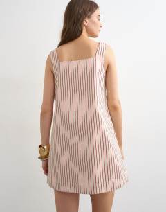 Model wearing Denim square neck pinny dress in ecru and red stripe