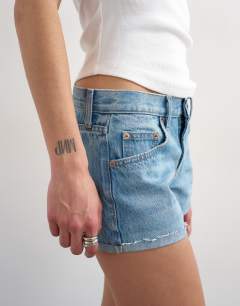 Model wearing Denim ultra mini short in mid blue