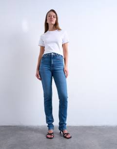 Model wearing Dree high rise slim straight leg jean in mid blue
