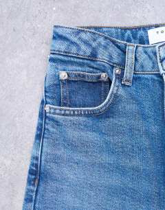 Model wearing Dree high rise slim straight leg jean in mid blue