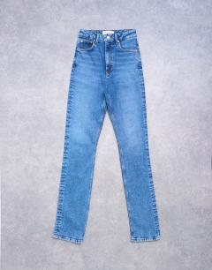Model wearing Dree high rise slim straight leg jean in mid blue