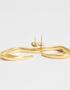 Model wearing Drew waterproof asymmetric hoop earring in gold