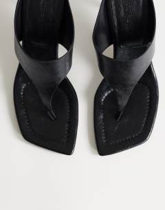 Model wearing Elodie toe thong mid heeled mule in black