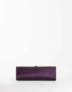Model wearing Ember small envelope satin clutch bag in aubergine