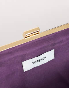 Model wearing Ember small envelope satin clutch bag in aubergine