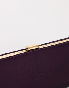 Model wearing Ember small envelope satin clutch bag in aubergine