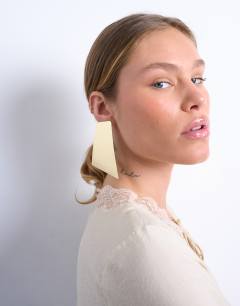 Model wearing Emmey statement stud earrings in gold