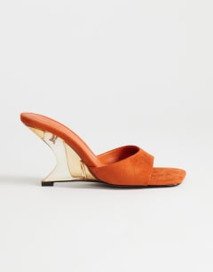 Model wearing Esme mule with clear wedge heel in orange