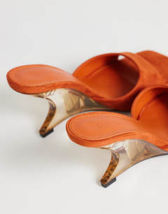 Model wearing Esme mule with clear wedge heel in orange
