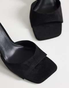 Model wearing Esme mule with clear wedge high heel in black
