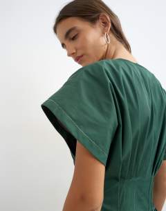 Model wearing Exaggerated shoulder cinched pintucked waist maxi dress in dark green with contrast topstitching