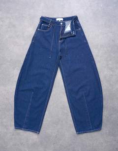 Model wearing Extreme barrel mid rise jean with belt detail in indigo rinse