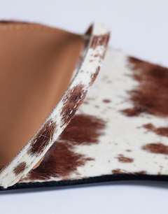 Model wearing Ezra strappy heel sandal in cow print hair on real leather