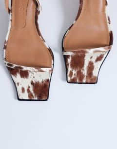 Model wearing Ezra strappy high heel sandal in cow print hair on real leather