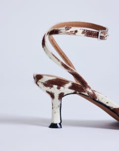 Model wearing Ezra strappy high heel sandal in cow print hair on real leather