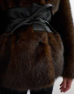 Model wearing Faux fur coat with faux leather belt in brown