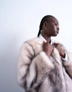 Model wearing Faux fur collarless mid length coat in white stripe