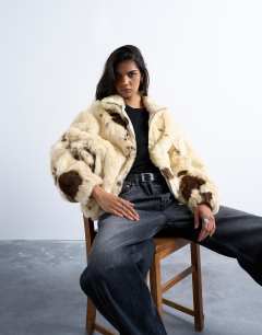 Model wearing Faux fur cow print funnel neck bomber jacket in cream