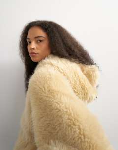 Model wearing Faux fur zip through hooded jacket in cream