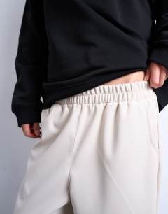 Model wearing Faux leather awkward length pull on trouser in ecru