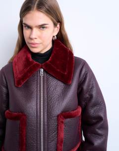 Model wearing Faux leather cropped jacket with red borg contrast