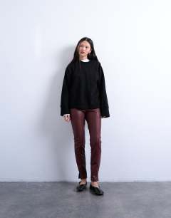 Model wearing Faux leather drain pipe skinny trouser in burgundy