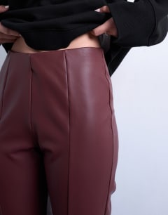 Model wearing Faux leather drain pipe skinny trouser in burgundy
