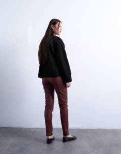Model wearing Faux leather drain pipe skinny trouser in burgundy