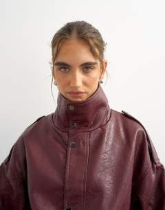 Model wearing Faux leather funnel neck drawstring bomber in burgundy