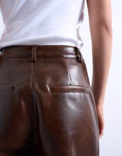 Model wearing Faux leather pleated straight leg trouser in rust