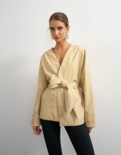 Model wearing Faux leather wrap tie detail top in buttermilk