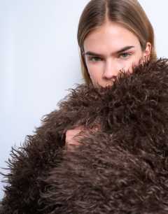 Model wearing Faux mongolian fur bomber coat in chocolate