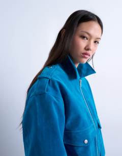 Model wearing Faux suede quilted lined bomber jacket with popper details in bright blue