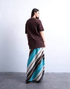 Model wearing Flood length cupro maxi bias skirt in brown and blue stripe