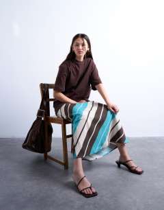 Model wearing Flood length cupro maxi bias skirt in brown and blue stripe